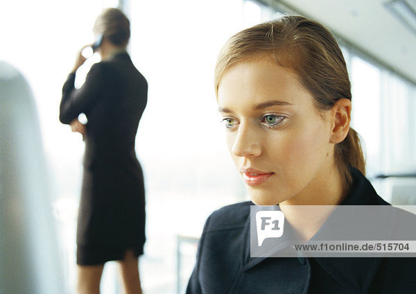 Geschäftsfrau am Handy  Rückansicht  im Hintergrund  verschwommen  Geschäftsfrau im Vordergrund  Nahaufnahme