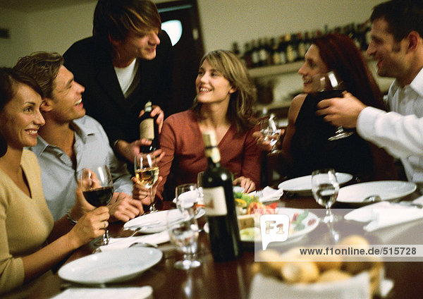 Gruppe junger Leute am Tisch  die Wein trinken