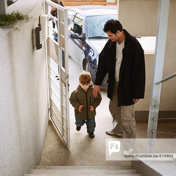 Vater kommt mit Sohn in die Tür  volle Länge  hoher Blickwinkel