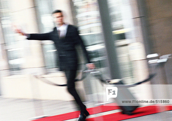 Businessman with luggage  arm extended  blurred