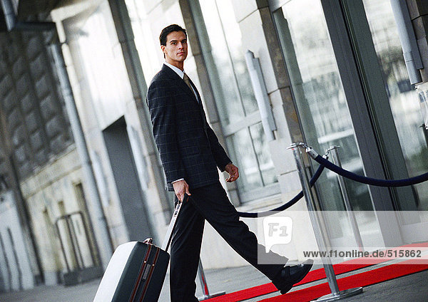Businessman walking with luggage outside  side view