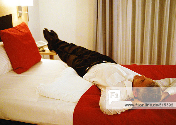 Businessman lying across bed