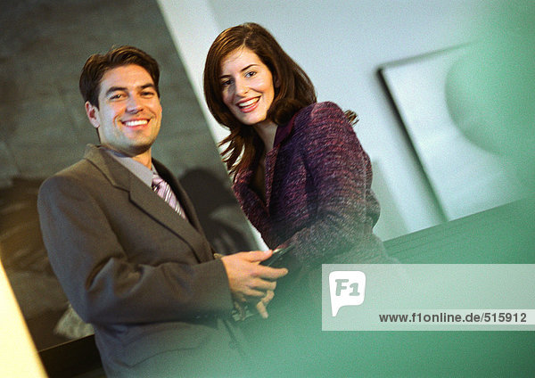 Businessman holding businesswoman's hand  smiling at camera