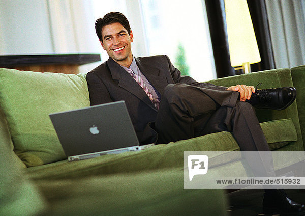 Geschäftsmann auf der Couch sitzend lächelnd vor der Kamera