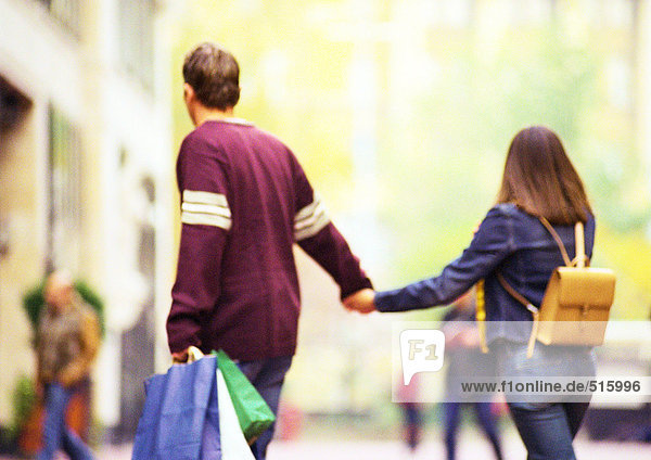 Couple shopping together  holding hands  view from behind.
