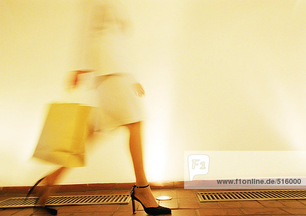 Woman in heels walking with shopping bag  side view  blurred motion