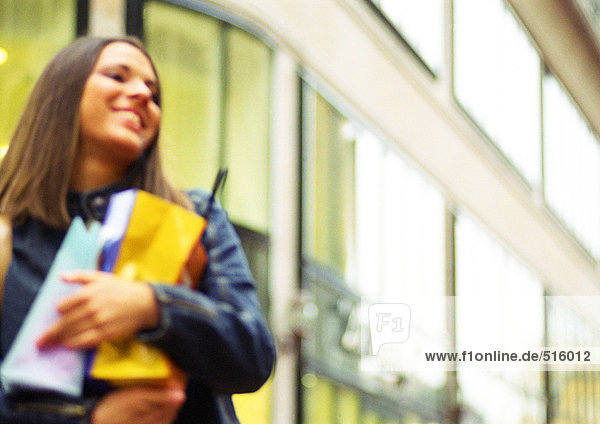 Young woman holding shopping bags in arms  smiling  blurred.