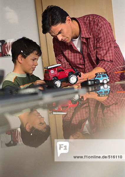 Vater und Sohn spielen mit Spielzeugautos.