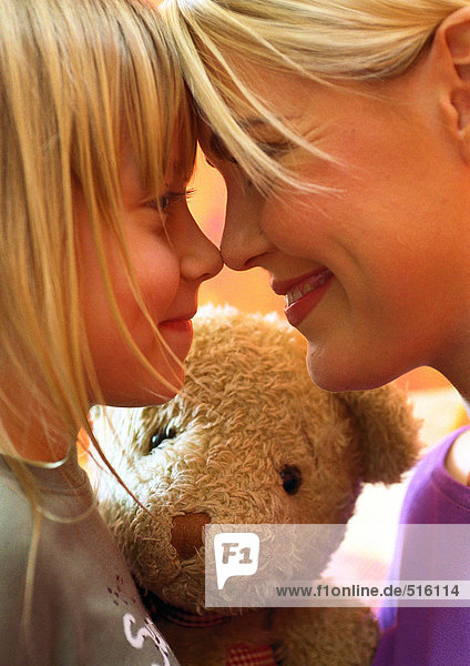 Frau und kleines Mädchen  Nase an Nase  Teddybär im Hintergrund