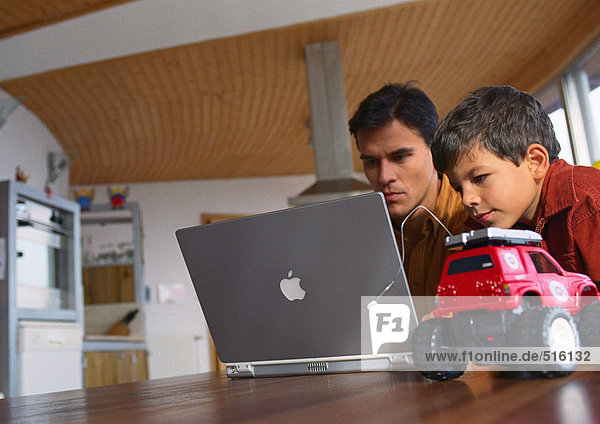 Vater und Sohn arbeiten zusammen am Computer.