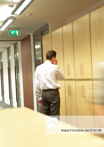 Businessman on phone standing in hallway.