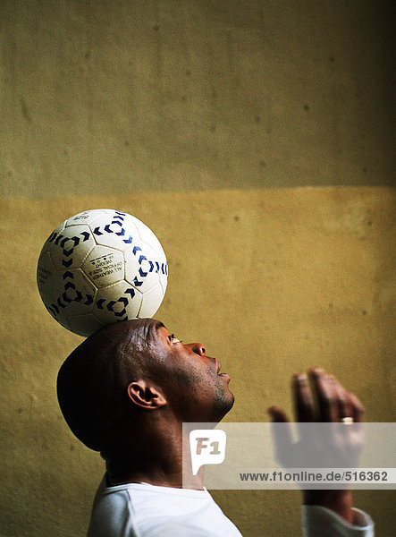 Profilansicht des Mannes beim Balancieren des Fußballs auf dem Kopf