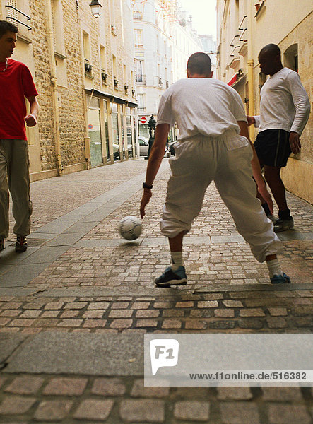 Männer spielen Fußball auf der Straße