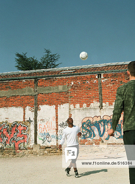 Männer spielen mit Fußball in der Stadt