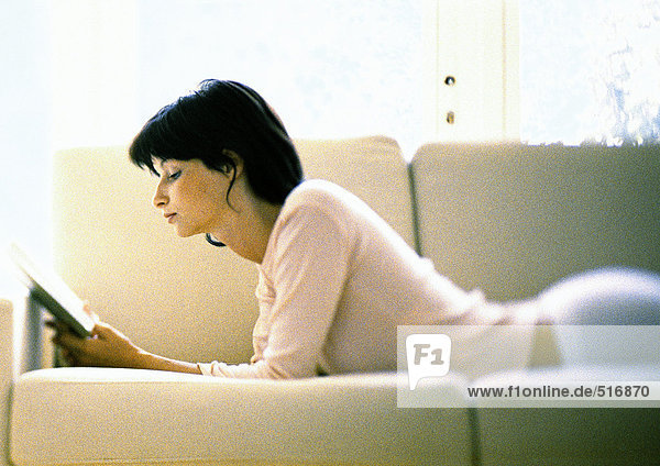 Frau auf dem Sofa liegend  lesend