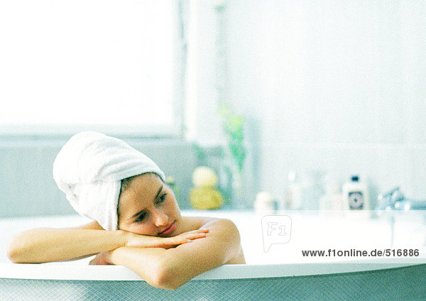 Frau in der Badewanne auf Wannenrand gelehnt  Haar in Handtuch gewickelt
