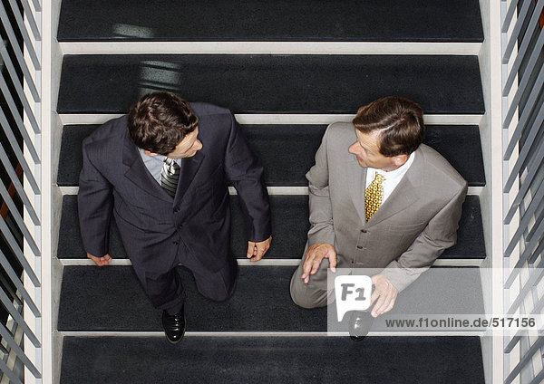 Zwei Geschäftsleute  die die Treppe hinuntergehen  erhöhte Ansicht