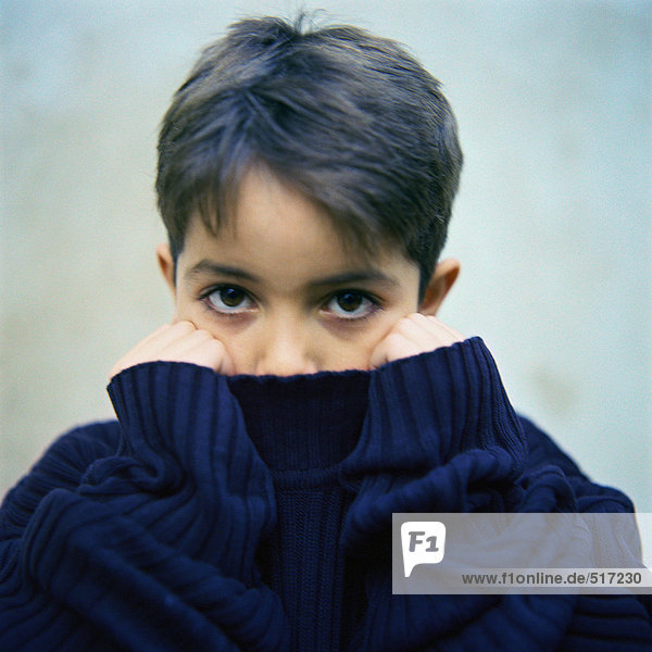 Junge mit Pullover-Kragen über dem Mund,  Portrait