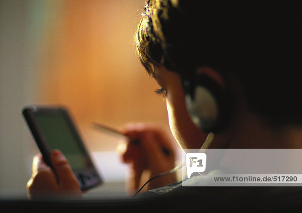 Young boy with headphones on using electronic organizer  close up