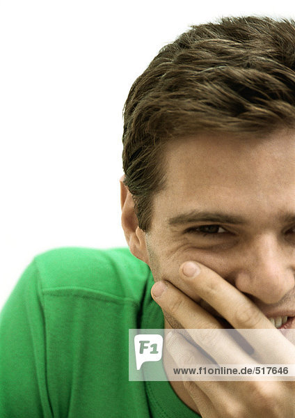 Man smiling covering mouth with hand  partial view  portrait