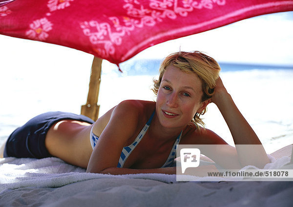 Frau am Strand unter dem Sonnenschirm liegend