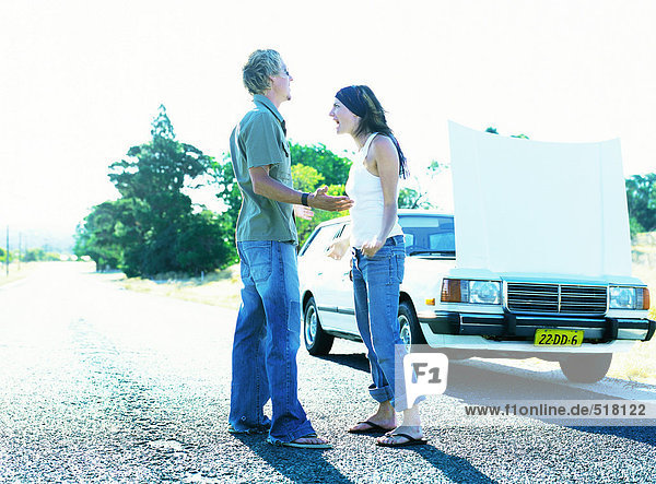 Mann und Frau stehen vor dem Auto mit offener Haube