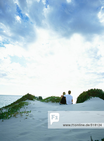 Paar auf Sanddüne mit Blick aufs Meer  Rückansicht