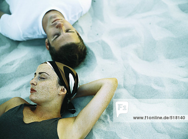 Paar auf Sand liegend  Augen geschlossen  erhöhte Ansicht