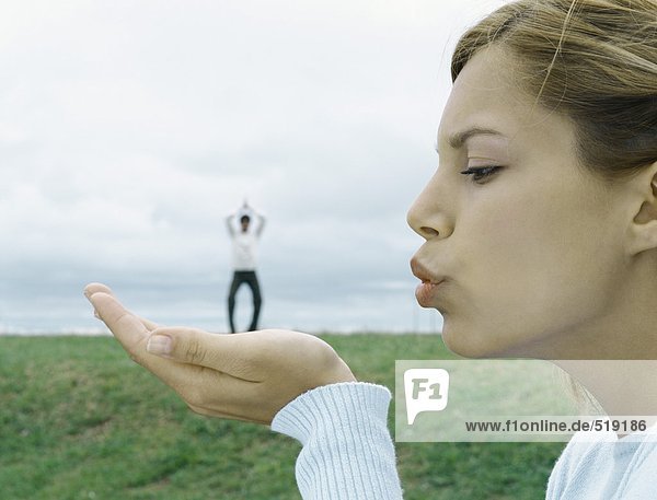 Frau bläst einen Kuss  Mann im fernen Hintergrund  optische Täuschung