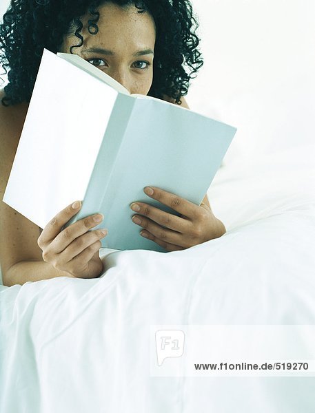Frau auf dem Bauch liegend auf dem Bett  Lesebuch