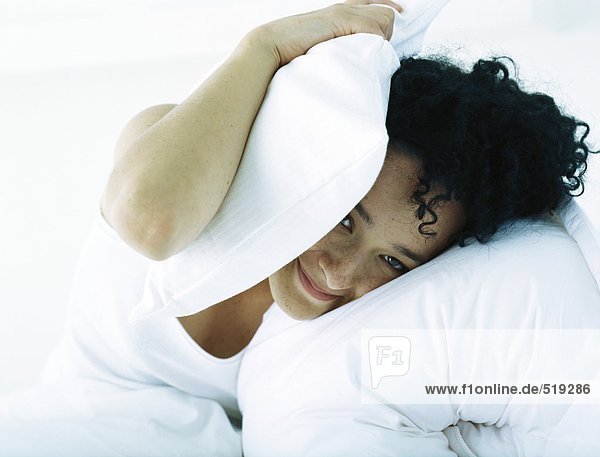 Frau im Bettdeckenkopf mit Kissen