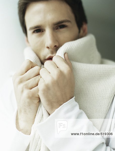 Man holding sweater around neck  covering part of face