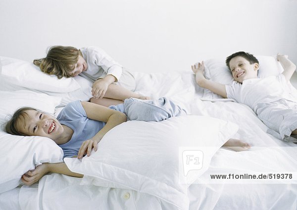 Boys and girl lying on bed laughing and smiling