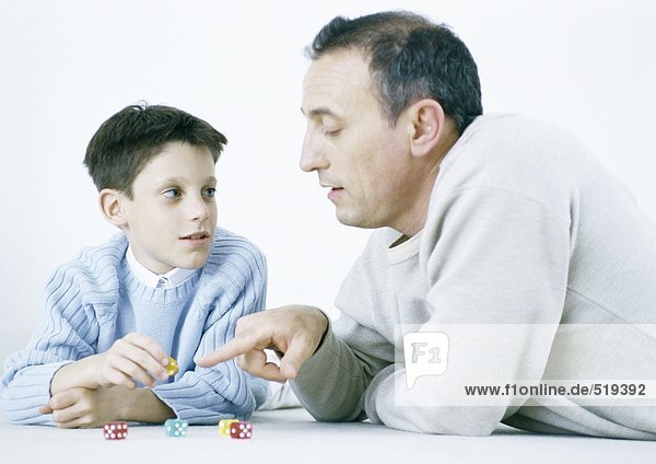 Father and son playing dice on floor
