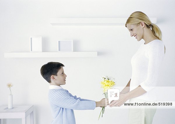 Boy holding out flowers to mother