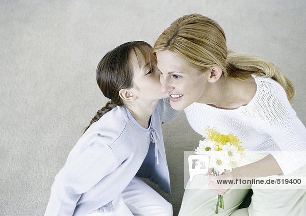 Frau hält Blumenstrauß  Mädchen küsst ihre Wange