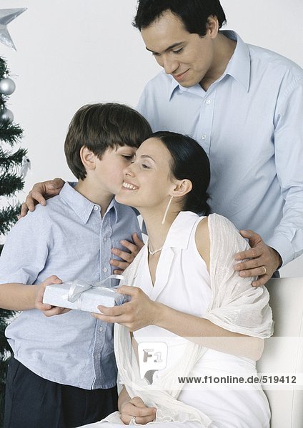 Boy giving gift to mother  father standing behind them