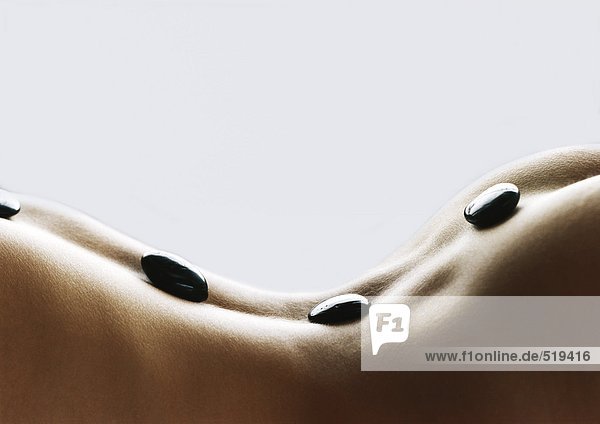 Frauenrücken gewölbt mit schwarzen Steinen auf dem Rücken  Nahaufnahme