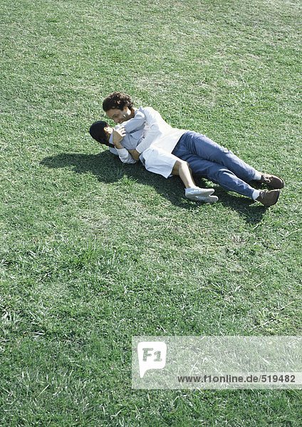 Mann und Tochter auf Gras in der Sonne liegend  Hochwinkelansicht