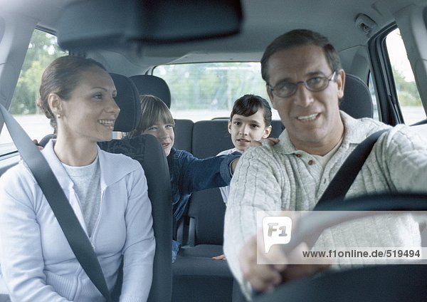 Eltern mit Jungen und Mädchen im Auto mit Sicherheitsgurten  Innenansicht