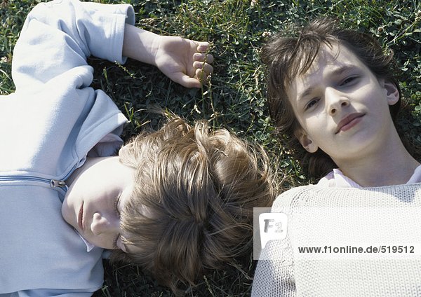 Mädchen und Junge auf Gras liegend