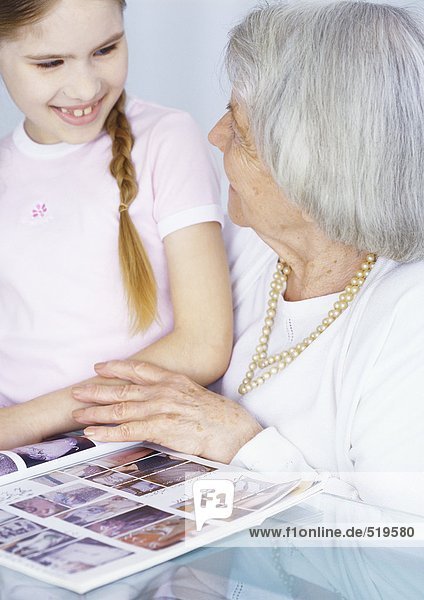 Großmutter und Enkelin schauen sich gemeinsam das Magazin an