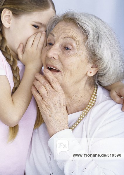 Mädchen flüsternd in Großmutters Ohr