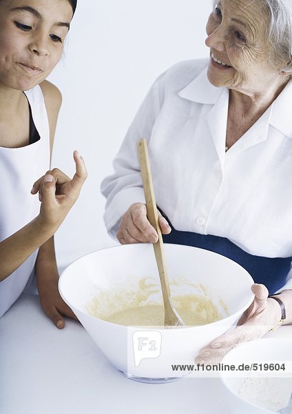Großmutter und Enkelin machen zusammen einen Teig.