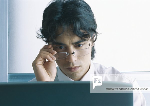 Geschäftsmann blickt auf den Computerbildschirm  schaut über die Brille