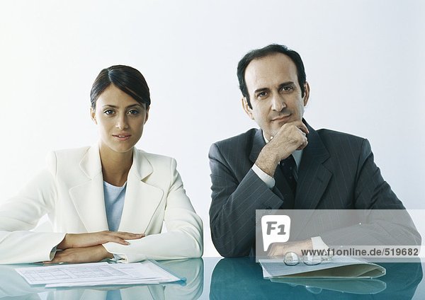Businessman and businesswoman sitting at table with documents