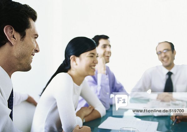 Businesspeople sitting around table together  laughing