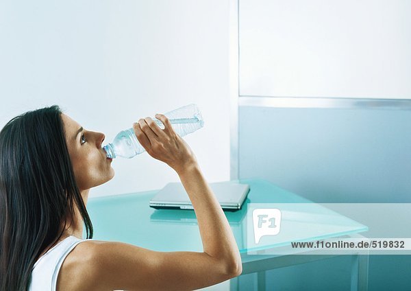 Frau trinkt aus Wasserflasche  Seitenansicht