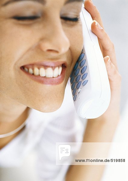 Woman talking on cordless phone with eyes closed  smiling