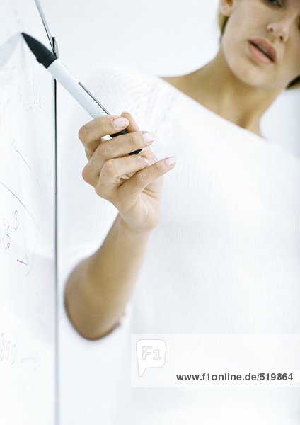 Frau zeigt mit Stift auf das Brett,  Teilansicht